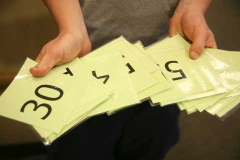 FIERCE COMPETITION FOR FITNESS CLASSES: A Wellness Center employee hands out laminated numbers to students waiting in line for the Zumba class. Recently due to popular demand , students have been forced to arrice at least 15 minutes before class time and even then often get denied.